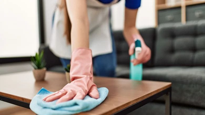 Professional residential cleaner wiping down a surface with eco-friendly products